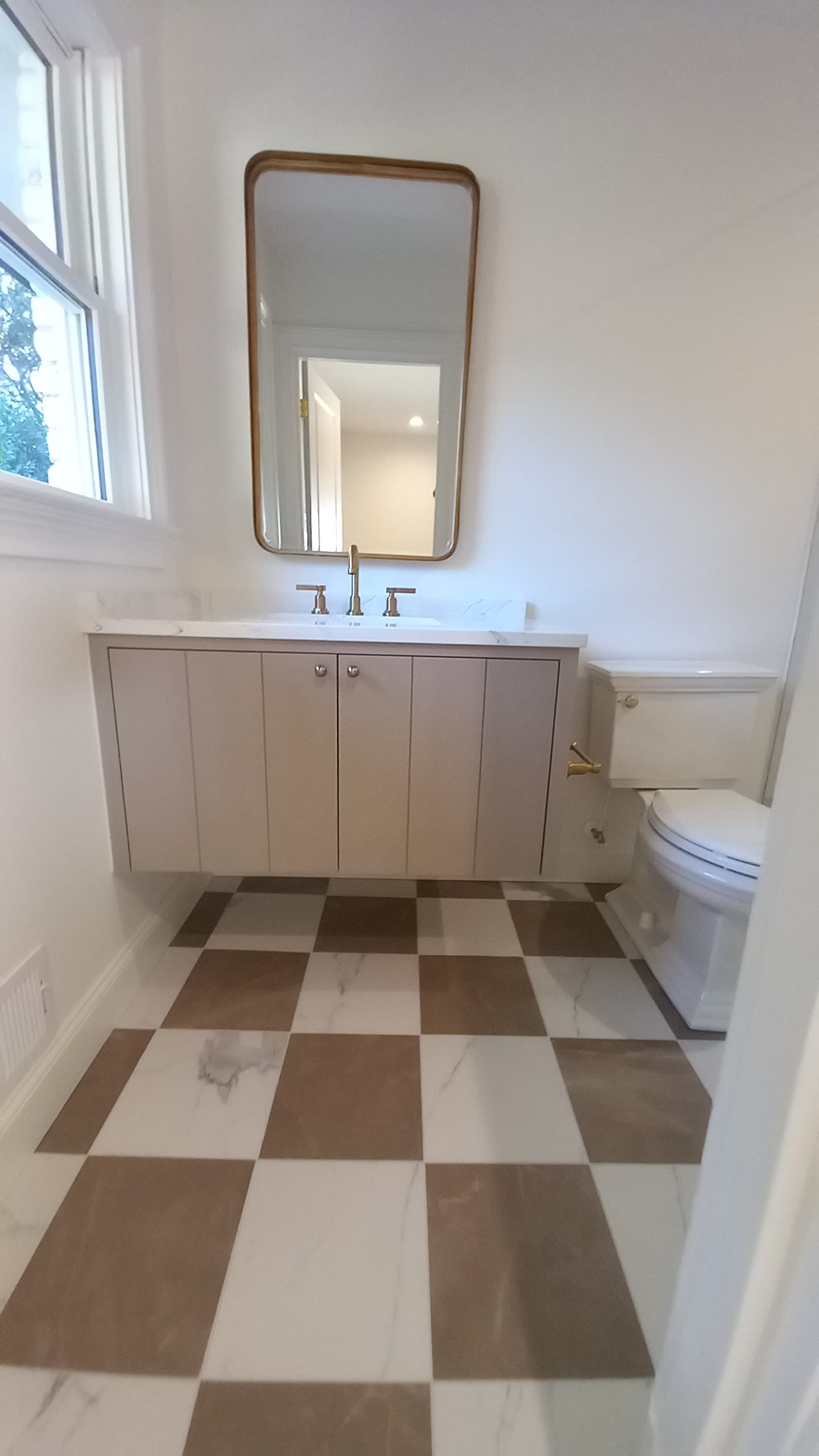 Floating custom vanity with a checkered tile floor in a bathroom remodel by Hdez Gabinets