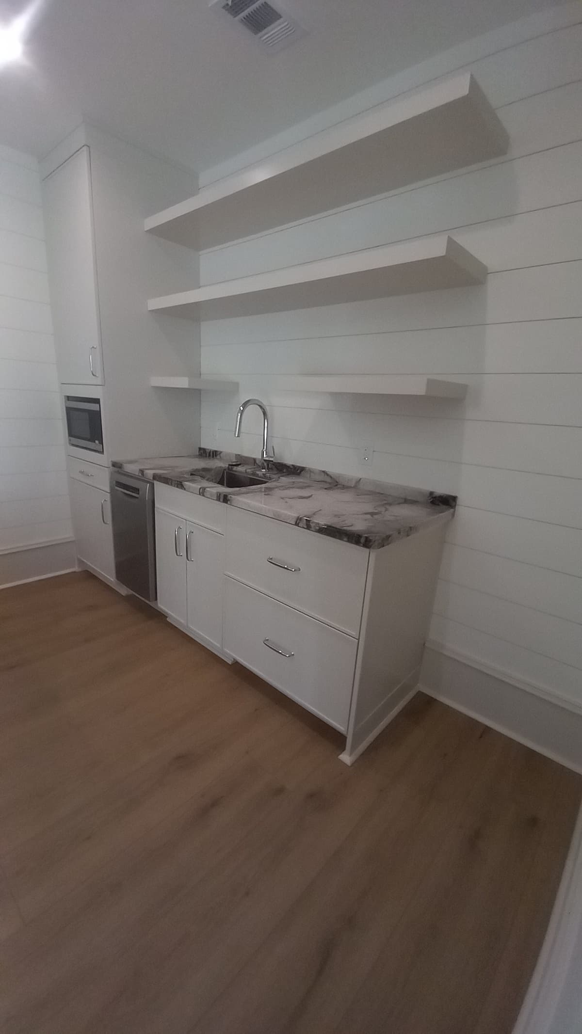 Custom kitchenette with floating shelves and a marble counter built by Hdez Gabinets