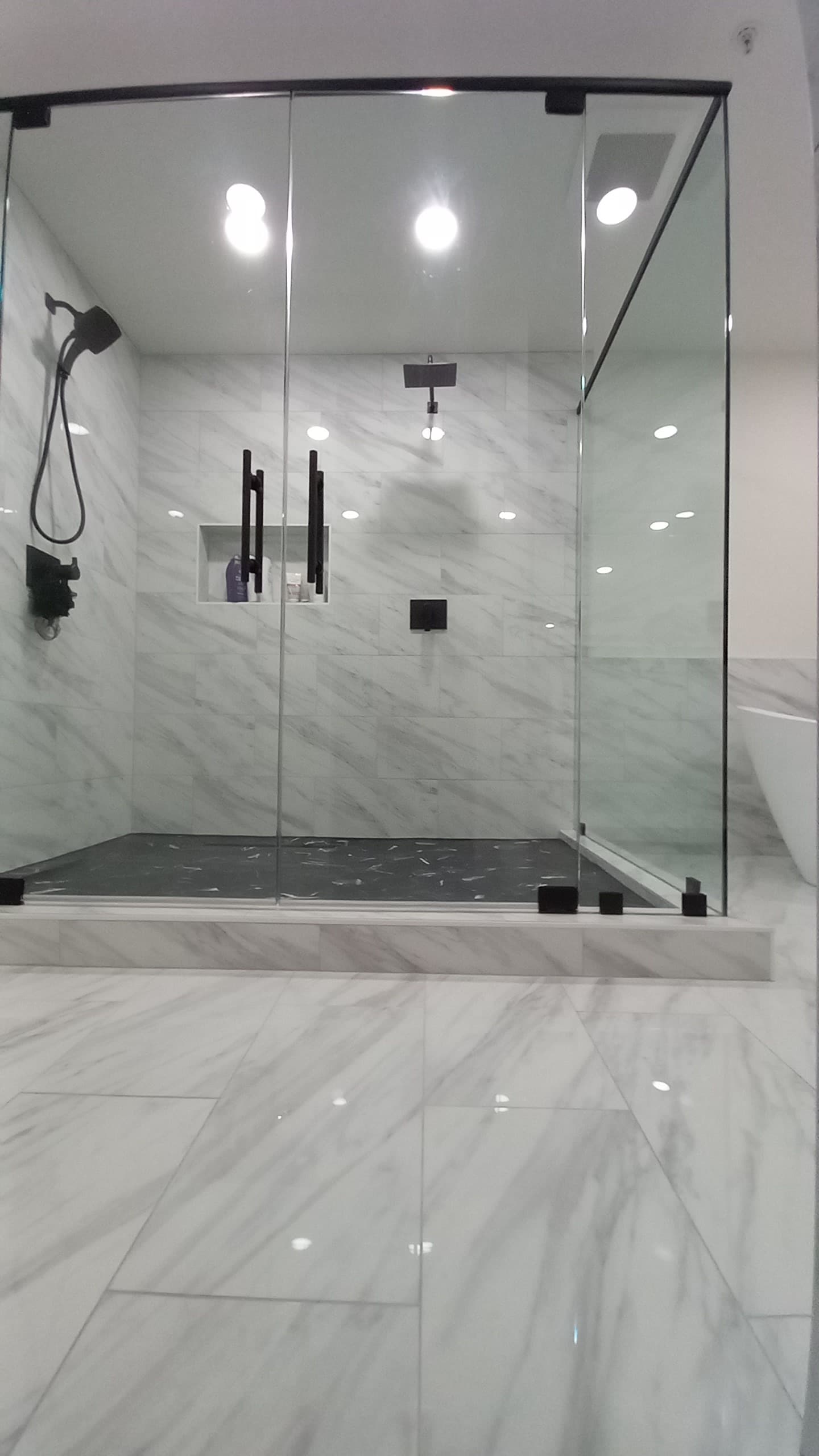 Walk-in glass shower with marble-look tile in a bathroom remodel by Hdez Gabinets in Atlanta